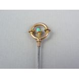 A late Victorian yellow metal and turquoise hat pin, having a turquoise cabochon held to the