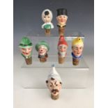 Seven vintage continental porcelain novelty bottle stoppers and spouts, modelled as the heads of