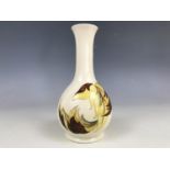 A Moorcroft pottery miniature bottle vase, decorated with autumnal leaves over a cream ground, paper