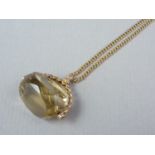 A citrine and yellow metal swivel fob seal converted to be worn as a pendant, on a 9ct gold curb