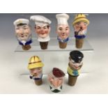 Seven vintage continental porcelain novelty bottle stoppers and spouts, modelled as the heads of