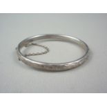 An Elizabeth II silver Charles Horner baby's bangle, the face engraved with stylized foliage,
