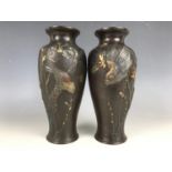 A pair of Meiji Japanese bronze vases, each of shouldered form and decorated in a high relief