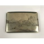 A mid 20th Century Japanese shakudo-inset white metal cigarette case, depicting in the round,