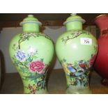 Pair of Chinese baluster form vases with covers decorated with exotic birds and flowers on a pale