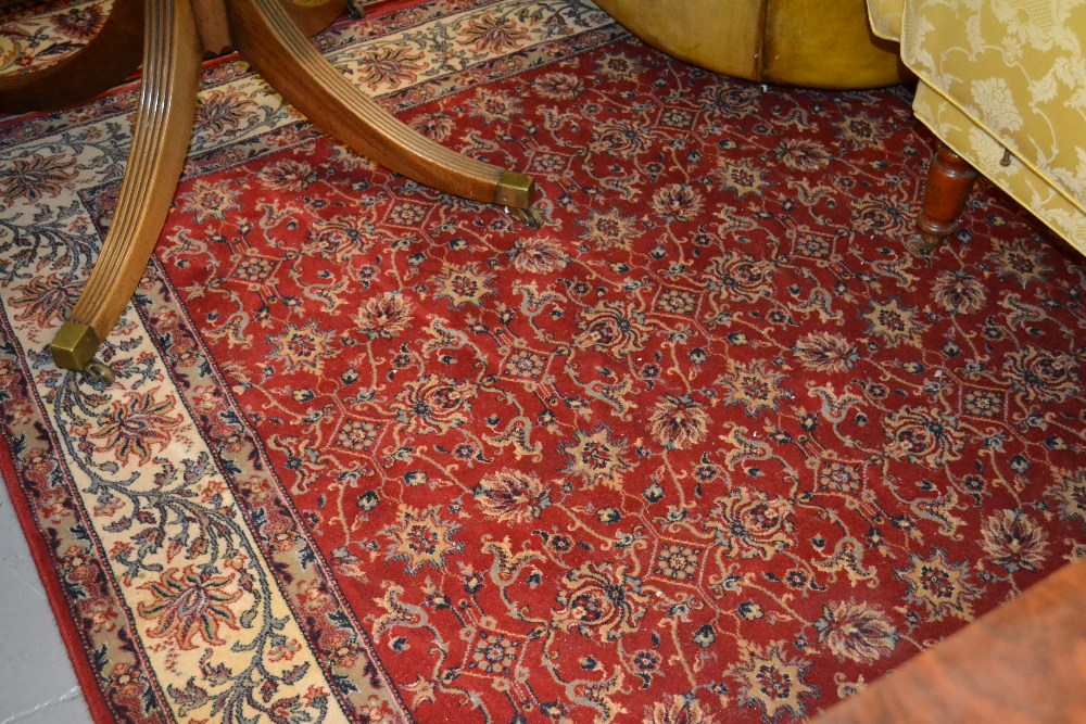 Machine woven Persian design carpet with floral pattern on red ground together with another similar