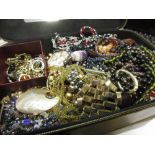 Black jewellery box containing a quantity of costume jewellery including various necklaces,