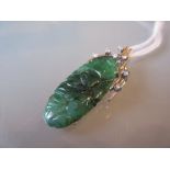 Carved green jade pendant in a white gold diamond set mount