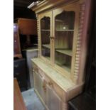 19th Century stripped pine bookcase / dresser, the moulded cornice above a pair of glazed doors,