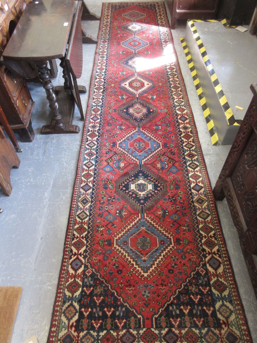 Indo Persian runner with repeating hooked medallion design on a red ground with borders,