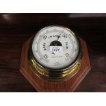 Brass cased circular marine barometer on a wooden base