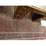 Kurdish rug with an all-over stylised floral and hooked medallion design on a brick red ground with