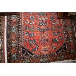 Kurdish rug with stylised tree of life design on a brick red field with borders,