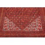 Antique Senneh rug of all-over Boteh design with multiple borders on a red ground,