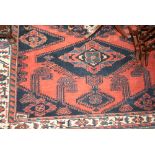 Kurdish rug with triple medallion design on a brick red ground with borders,