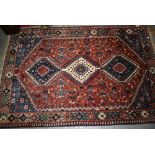 Small South West Persian rug with a triple hooked medallion and all-over design on a red ground