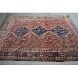 Shiraz carpet with triple pole medallion and all-over stylised design on a rust ground with borders,