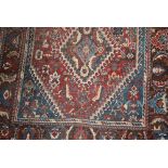 Shiraz rug with a triple hooked medallion and all-over design on a red ground with borders,