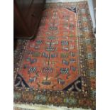 Kurdish rug with stylised tree of life design on a brick red field with borders,