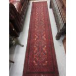 20th Century Belouch runner having hooked medallion design with multiple borders on a red and blue