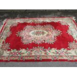 Chinese woollen floral decorated rug on a red ground