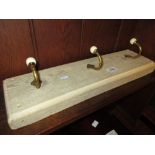 Set of three gilt brass and ceramic coat hooks on a lime waxed backboard