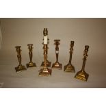 Three pairs of brass candlesticks on square set bases together with another similar table lamp