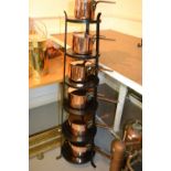 Graduated set of six copper saucepans with lids on a black painted iron stand