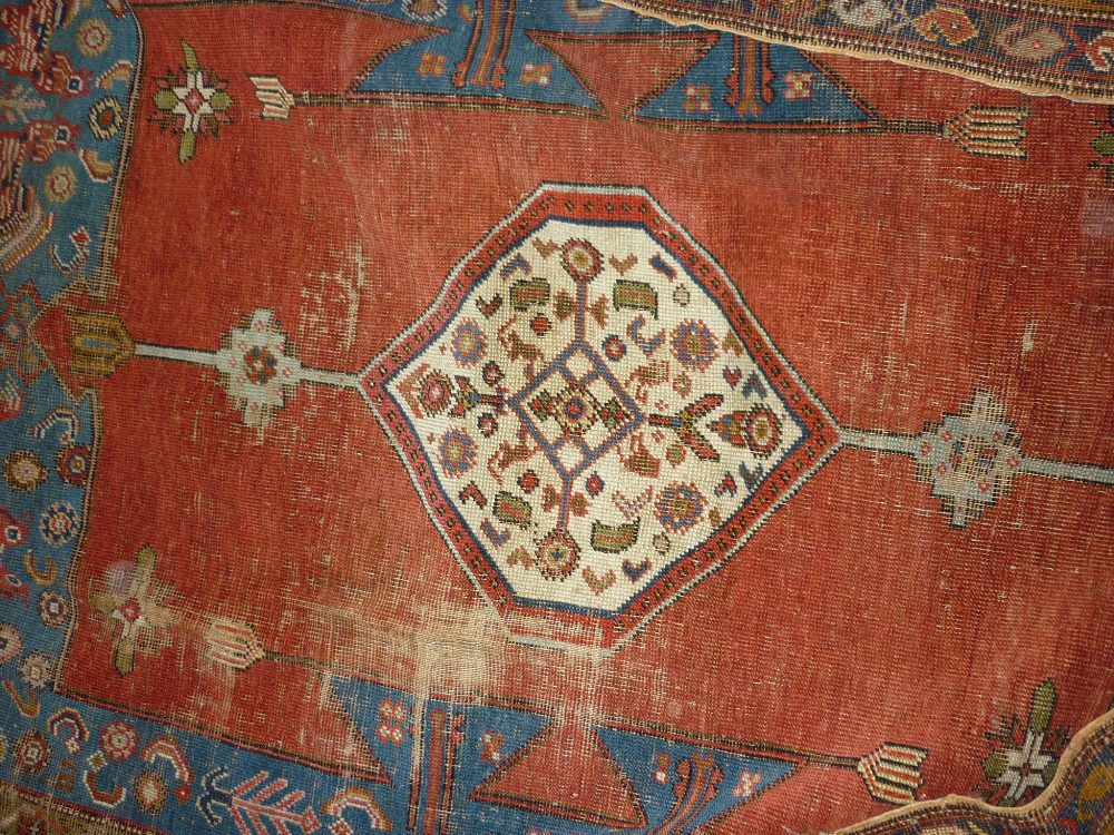 Kurdish rug with a single lobed medallion design on a red ground with multiple border,