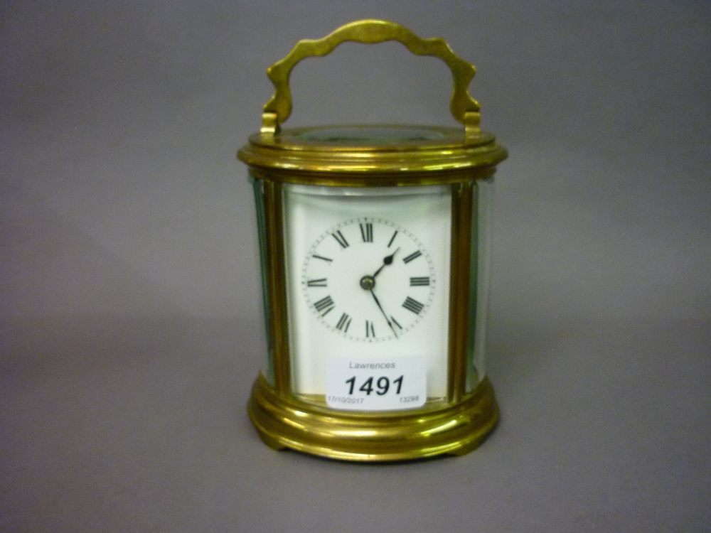 Early 20th Century oval gilt brass carriage clock, the enamel dial with Roman numerals,