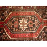 Kurdish rug having multiple medallion design with borders on a dark brown and burgundy ground,