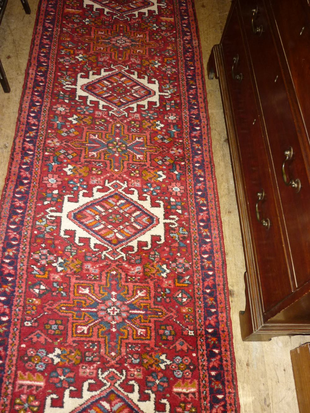 Modern central Persian runner with repeating medallions on a red ground,