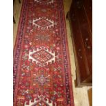 Modern central Persian runner with repeating medallions on a red ground,