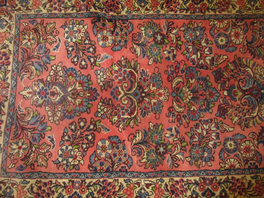 Sarouk runner with all-over floral design and multiple borders on a pink ground,