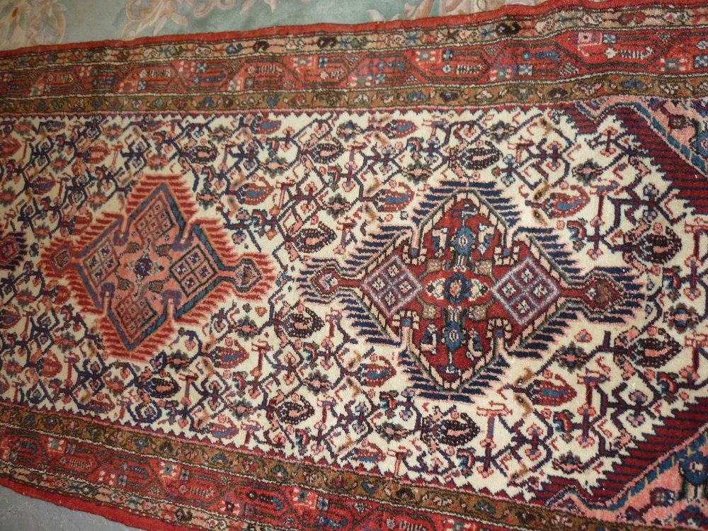 Hamadan runner with triple medallion and all-over design on an ivory ground with borders,