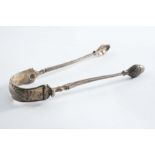 A PAIR OF GEORGE III CAST ARM SUGAR TONG with feather-edging, acorn-shaped bowls & a chased "u"