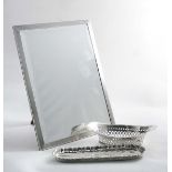 A RECTANGULAR MIRROR FRAME with an engine-turned border, bevelled glass & wooden easel back, maker's