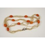 A SEED PEARL AND AMBER SET NECKLACE formed with five strands of small seed pearls, mounted with oval