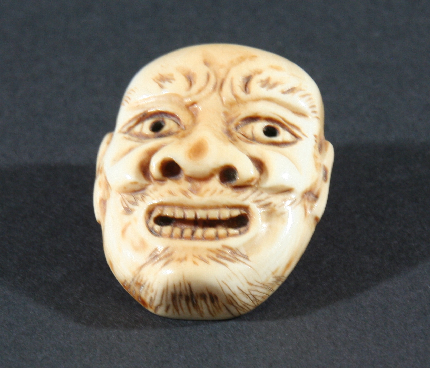 FOUR JAPANESE IVORY NETSUKE, the first carved as a grinning mask, height 4.3cm, together with a