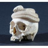 JAPANESE IVORY OKIMONO, carved as a detailed skull with a snake coiling around the crown, height 5.