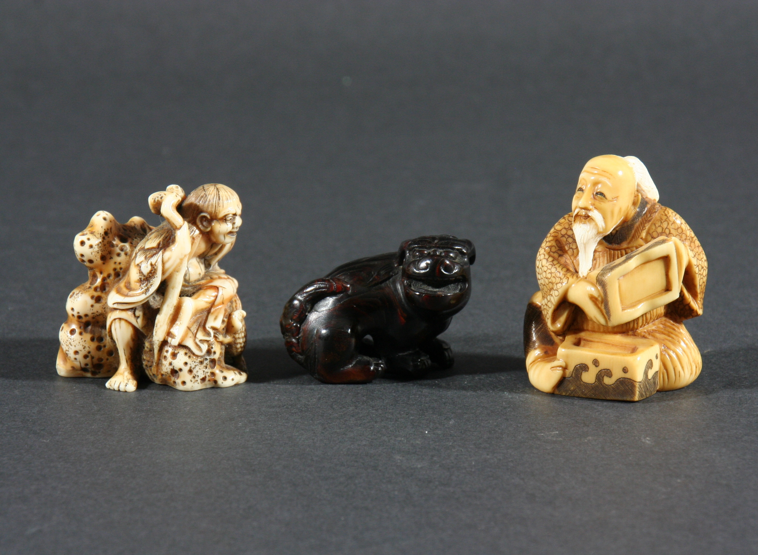 JAPANESE IVORY NETSUKE, carved as a figure seated on a rock with a three legged toad, signed,