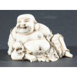 JAPANESE IVORY OKIMONO, carved as a hairy, reclining buddha, signed, height 7.5cm