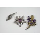 A SILVER FLOWERHEAD BROOCH centred with a circular-cut amethyst, 6cm. wide, together with two