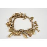 A 9CT. GOLD CHARM BRACELET set with assorted gold charms, 33 grams.