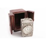 A LATE VICTORIAN EMBOSSED CARRIAGE TIMEPIECE with a decorated, cream coloured dial & black Roman