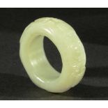 CHINESE PALE CELADON JADE THUMB RING, with carved scrolling decoration, diameter 5cm