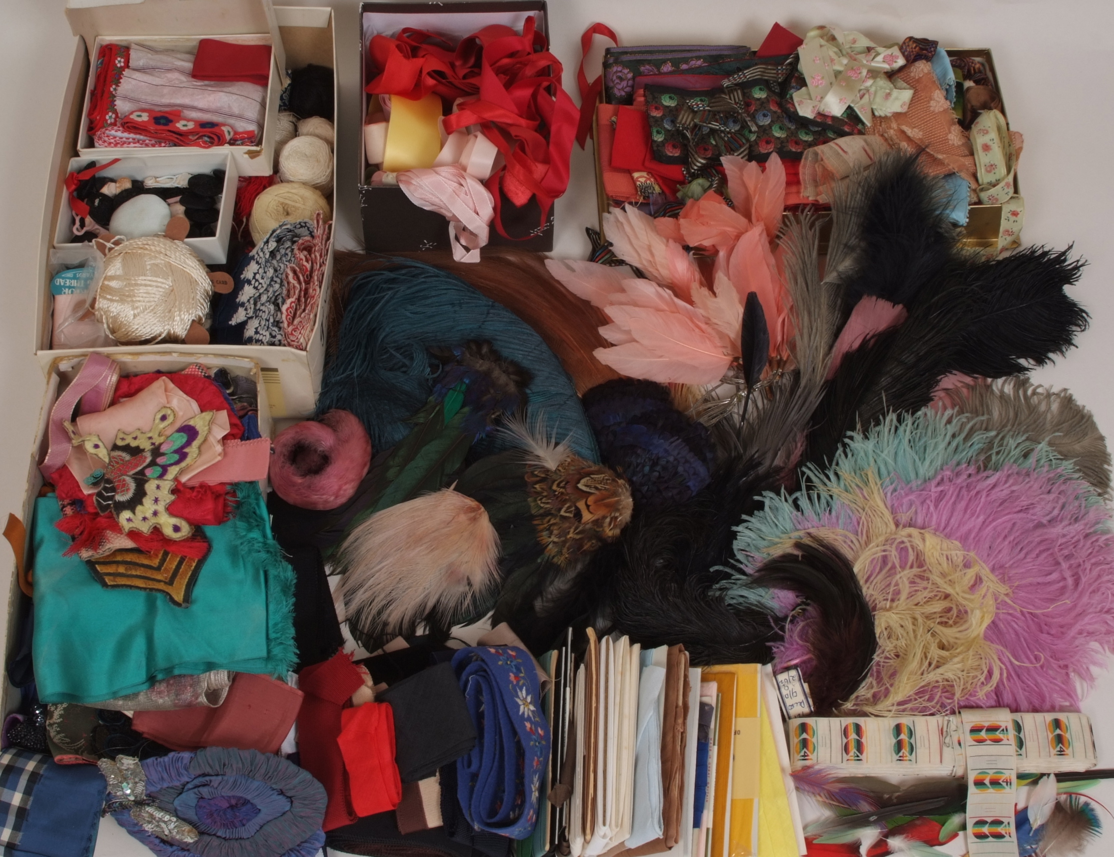 A COLLECTION OF HABERDASHERY AND MILLINERY ITEMS A quantity of feathers, ribbons and a roll of