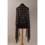 A BLACK AND SILVER ASSUIT SHAWL A black net shawl with silver metal embellishments. 85" long x 21"