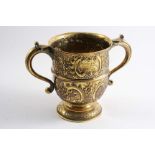 A LATE VICTORIAN SILVERGILT TWO-HANDLED CUP with embossed and chased decoration and a small