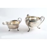 AN EDWARDIAN THREE-HANDLED SUGAR BOWL on pad feet with a plain circular body, by E.S. Barnsley,